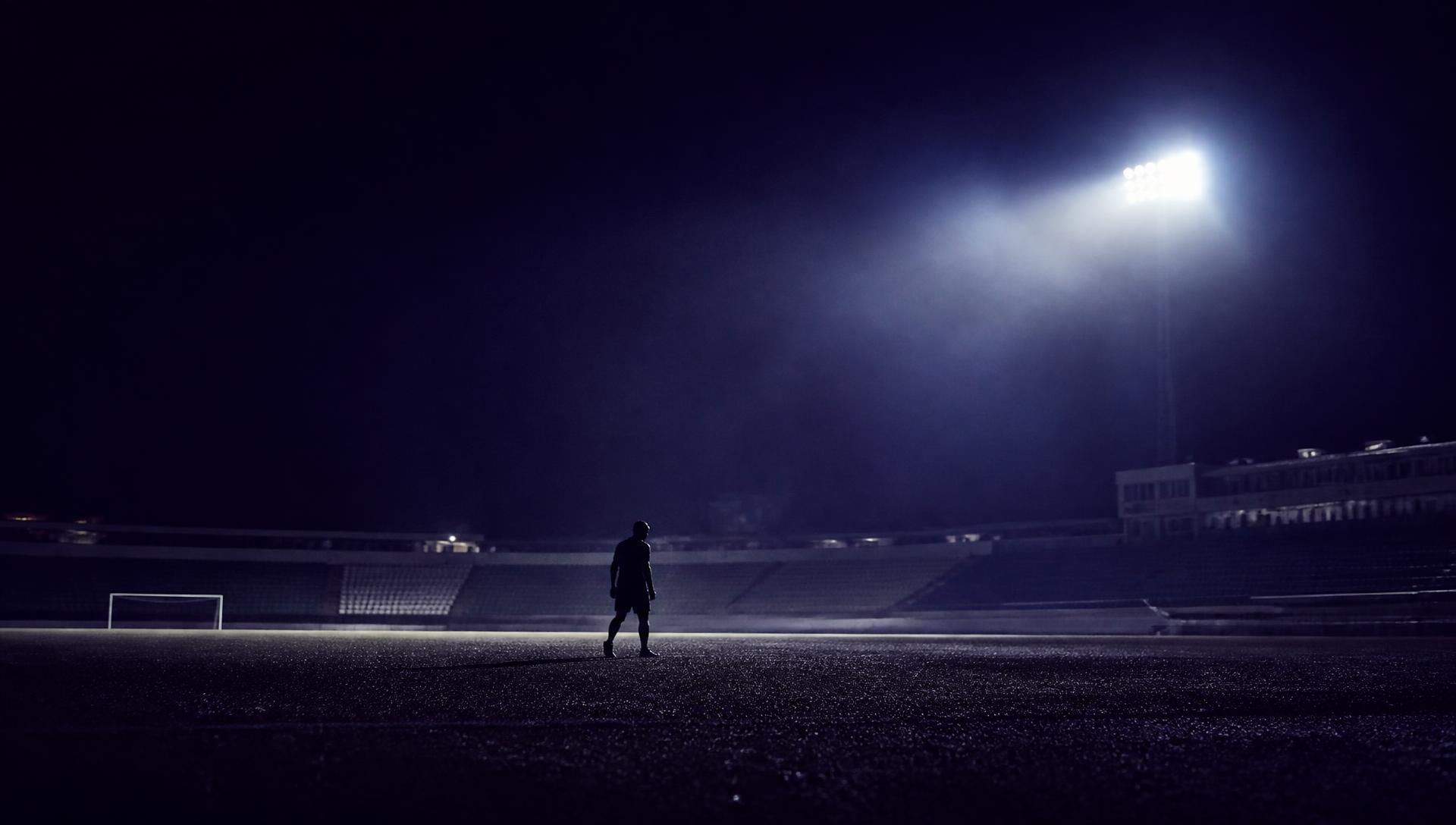 Player looking across a football field under stadium lights